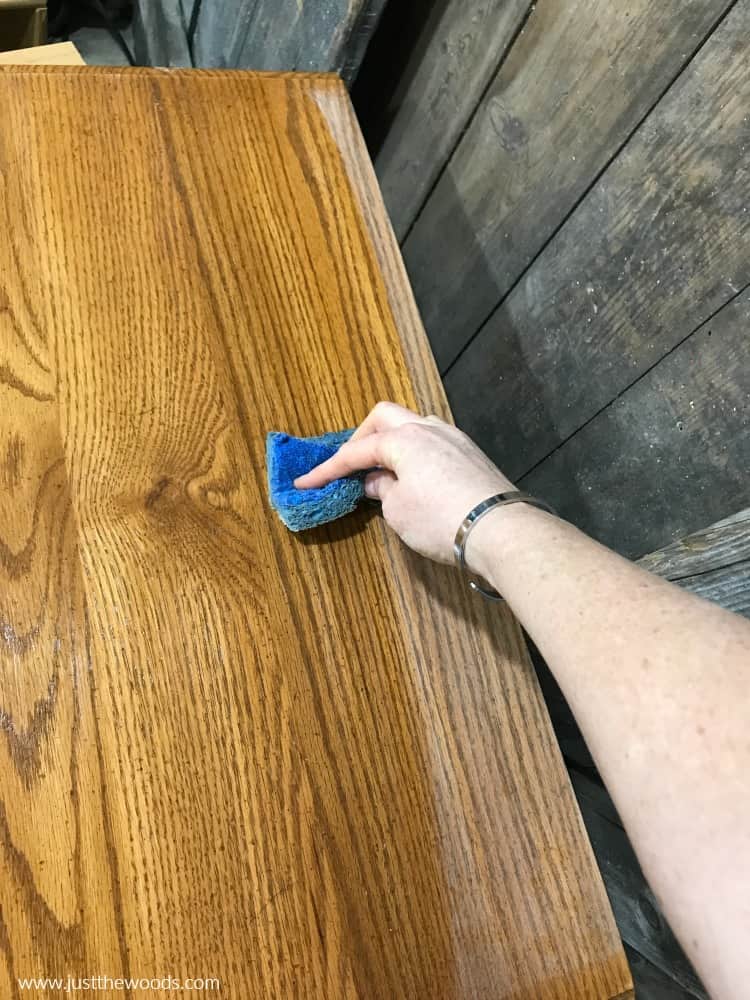 blue sponge cleaning dust off of wood furniture