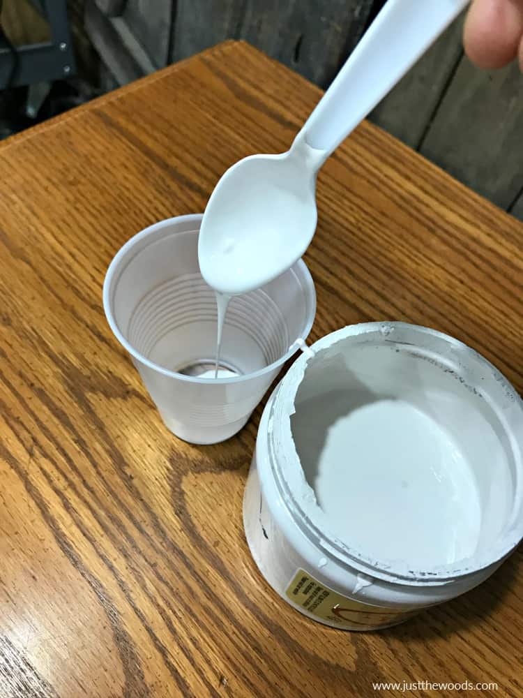 scoop white paint into cup with spoon, spoon white chalk paint into cup