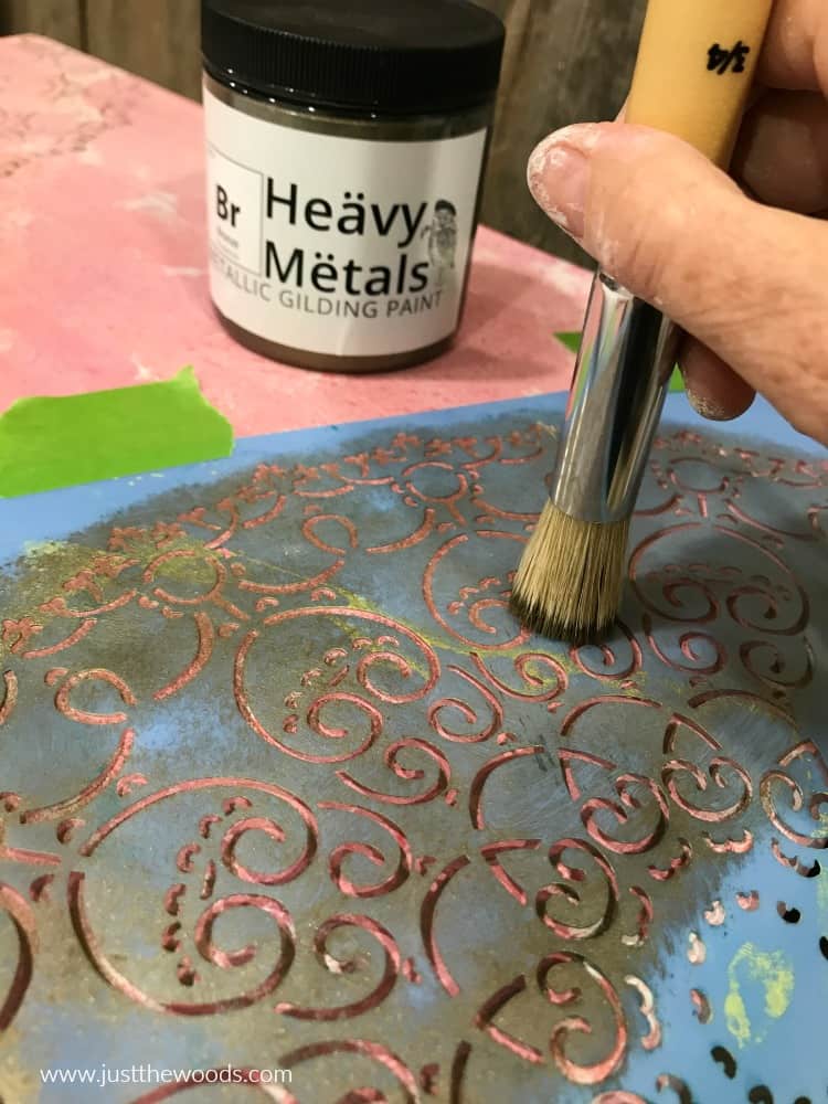close up stencil stencil brush and stencil with metallic paint in background