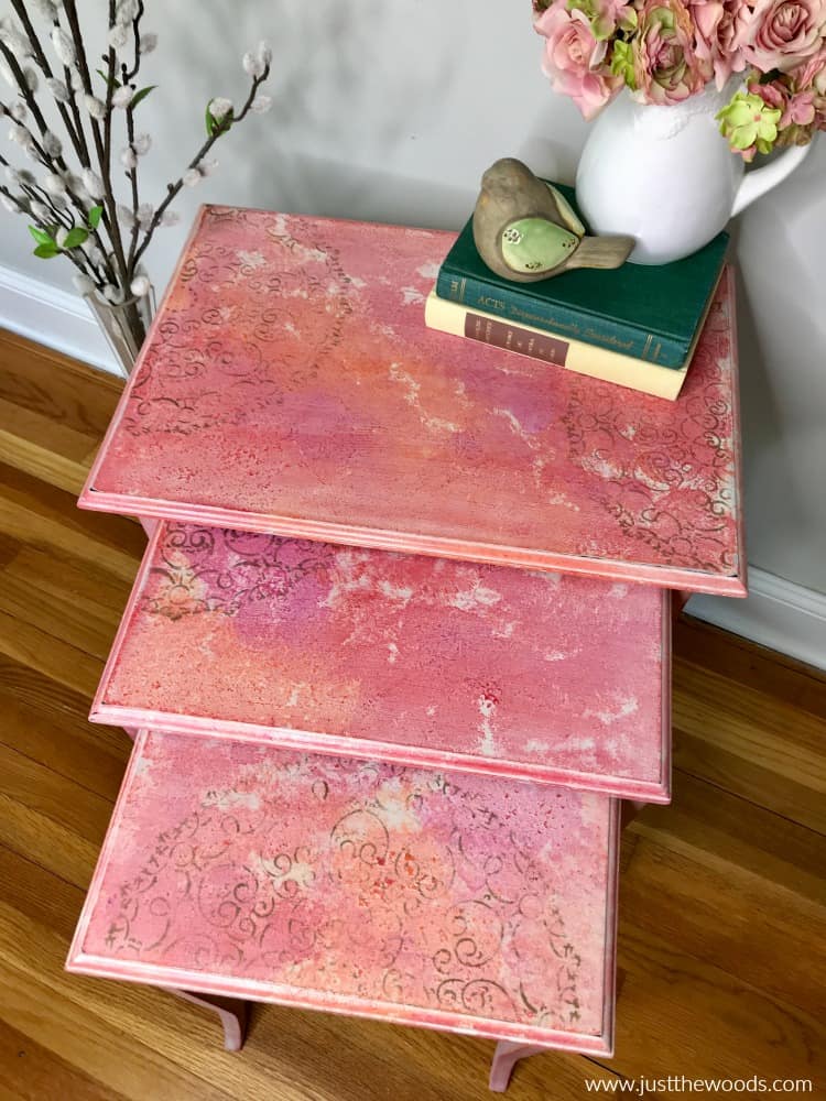 view of table tops of nesting table makeover. watercolor effect on pink painted furniture with stencil design