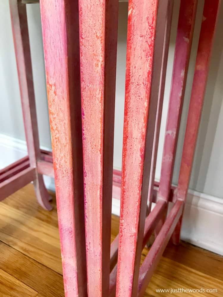 close up painted table legs with pink orange and red texture and whitewash creating a watercolor effect