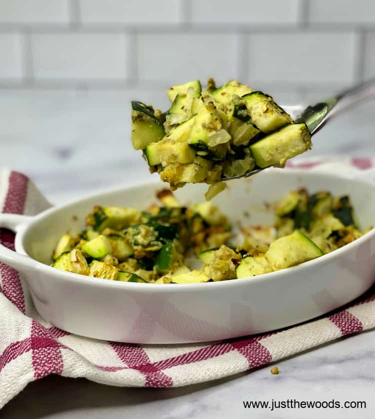 paleo zucchini casserole in a white dish with fork on red and white dishtowel 