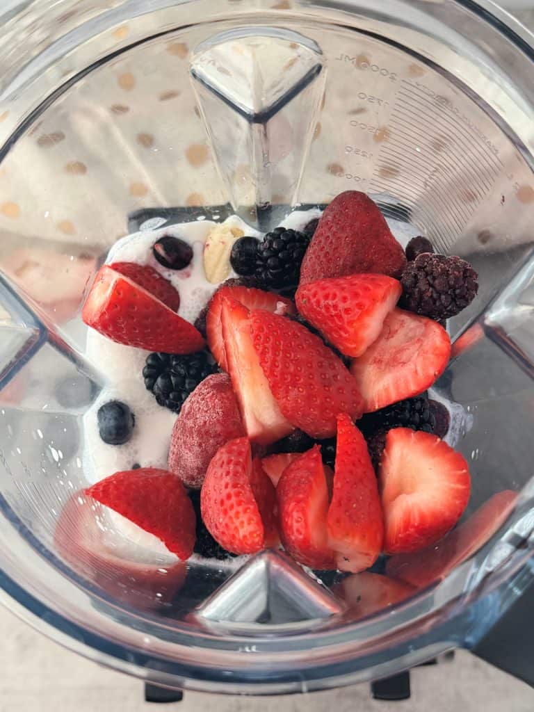 strawberries blackberries banana blueberries in blender with almond milk