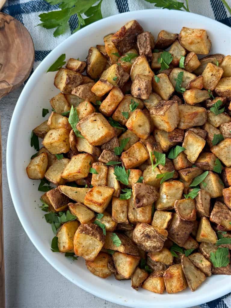 air fryer potatoes with fresh parsley in white dish 