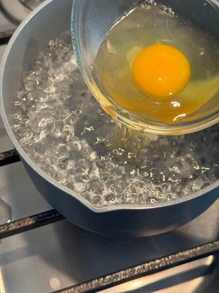 drop cracked egg into simmering hot water