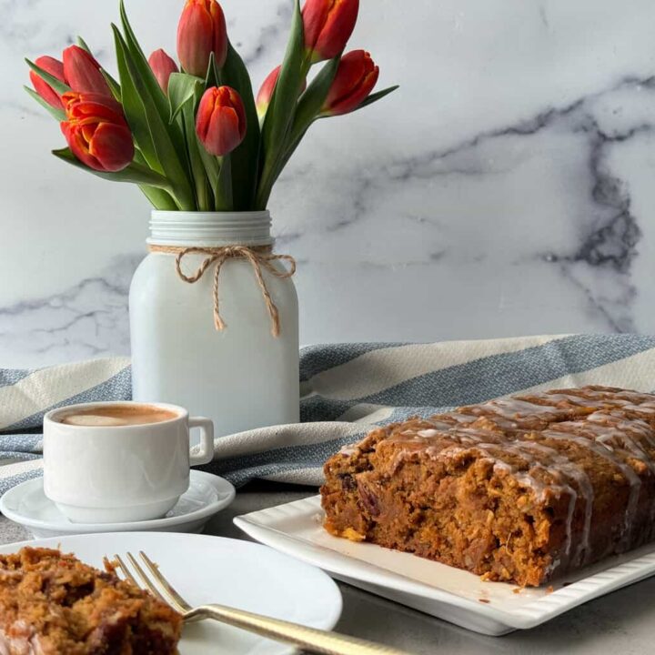 healthy carrot cake on white platter with flowers in vase