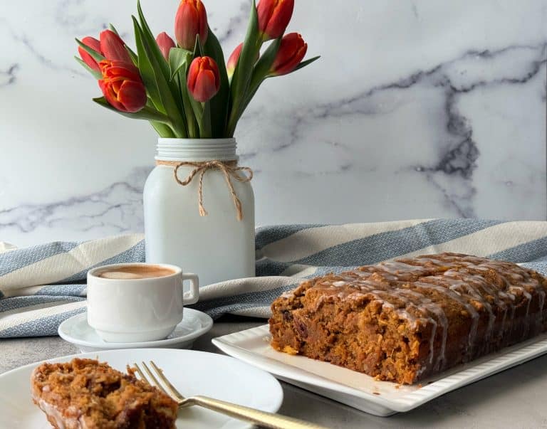 healthy carrot cake on white platter with flowers in vase