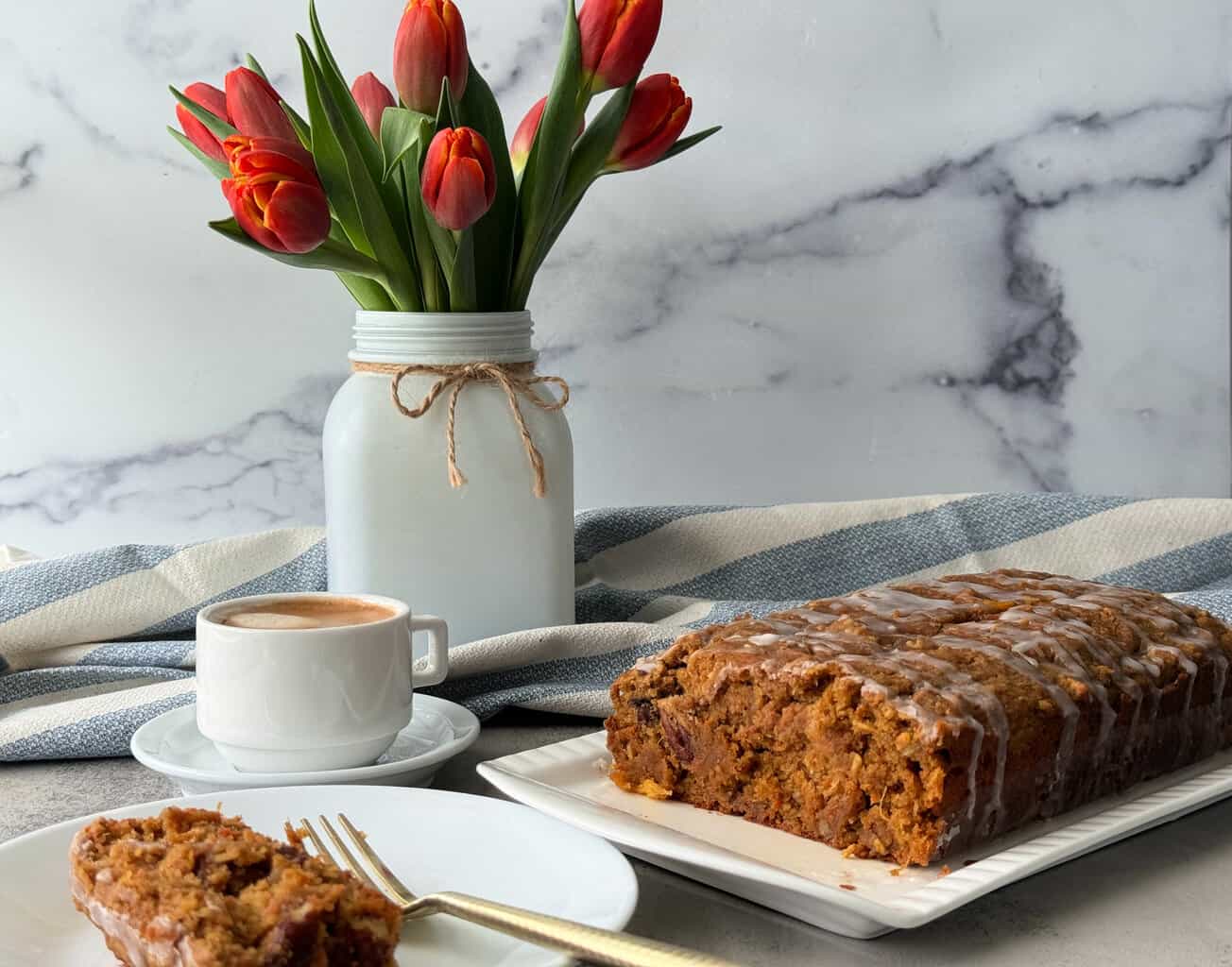 healthy carrot cake on white platter with flowers in vase