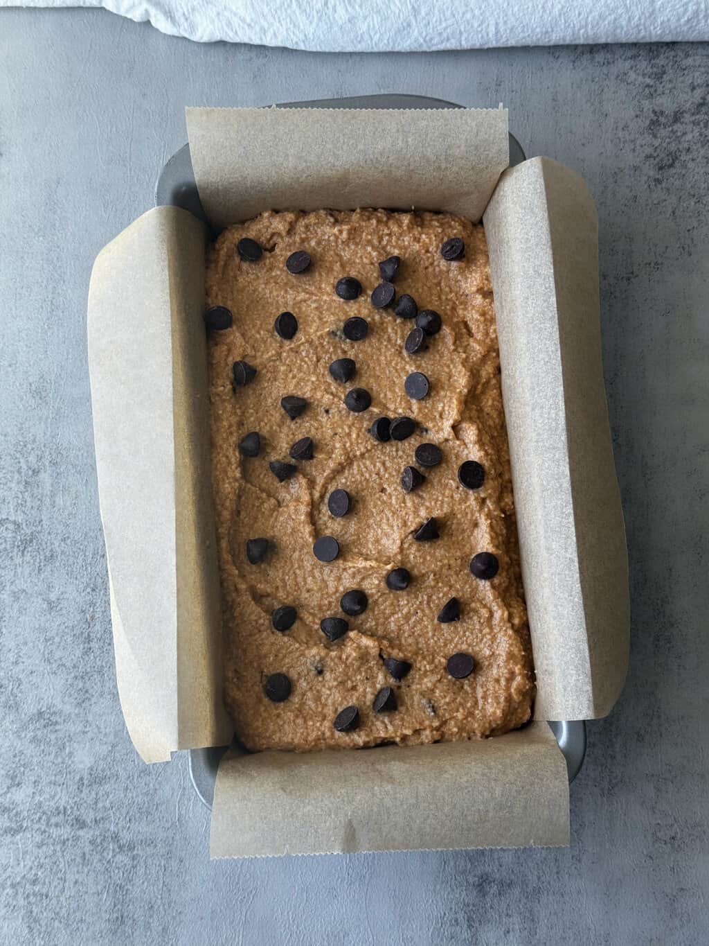 pumpkin bread batter in loaf pan with cacao chips on top