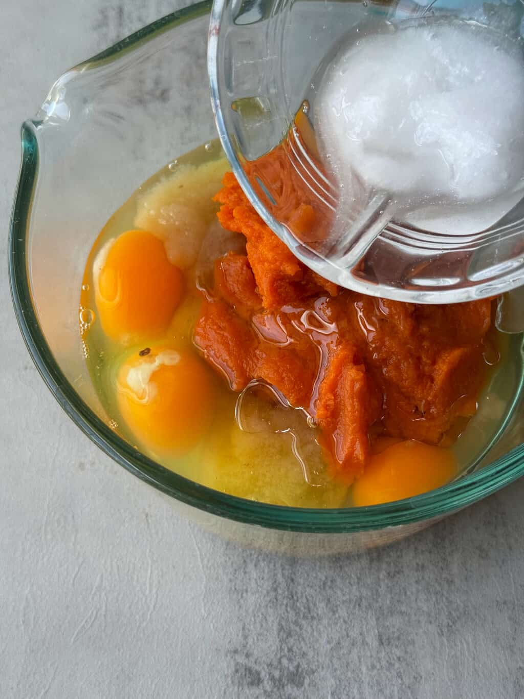 coconut oil an a glass bowl with pumpkin applesauce and eggs