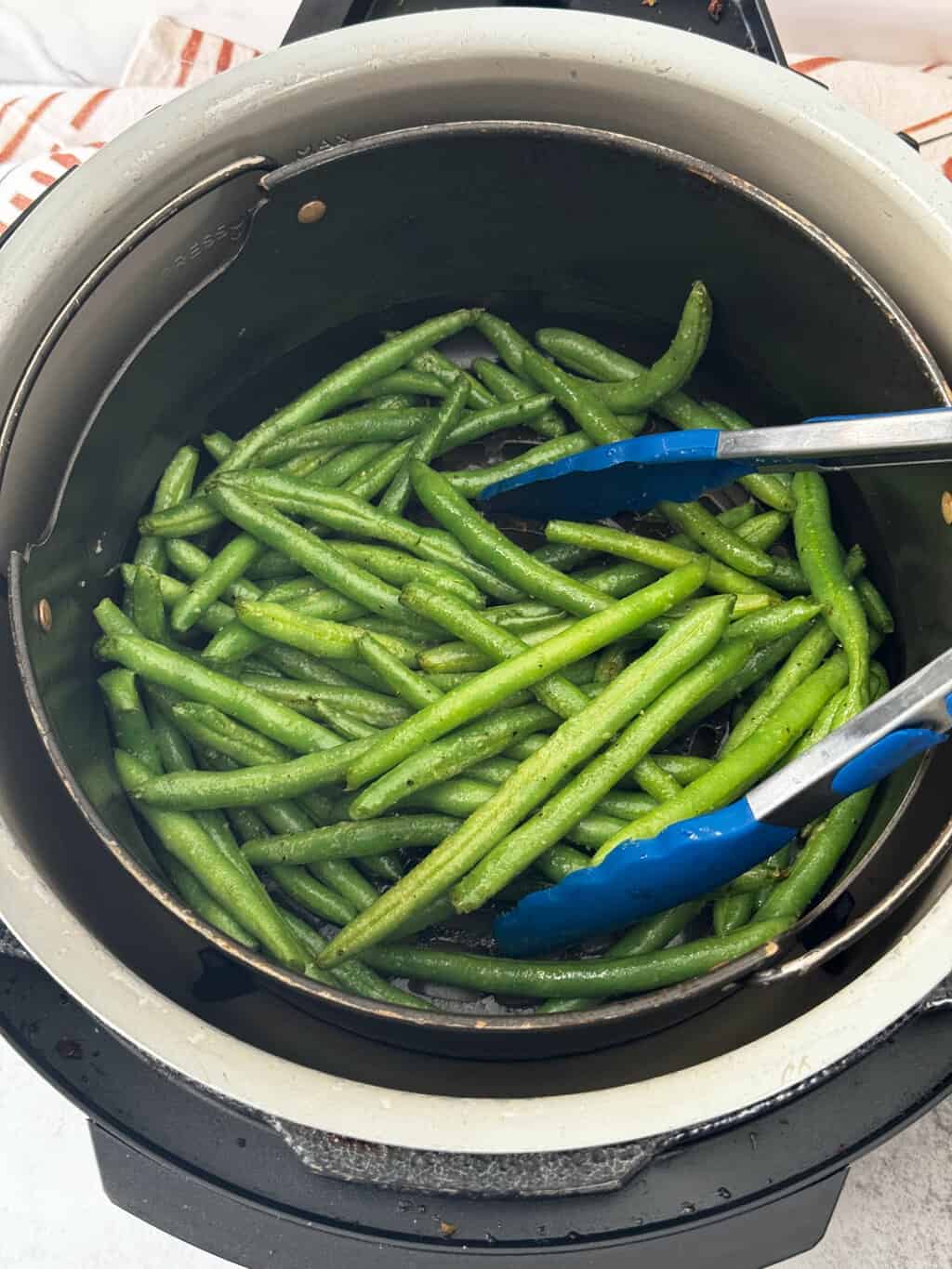 toss fresh string beans with tongs in air fryer basket