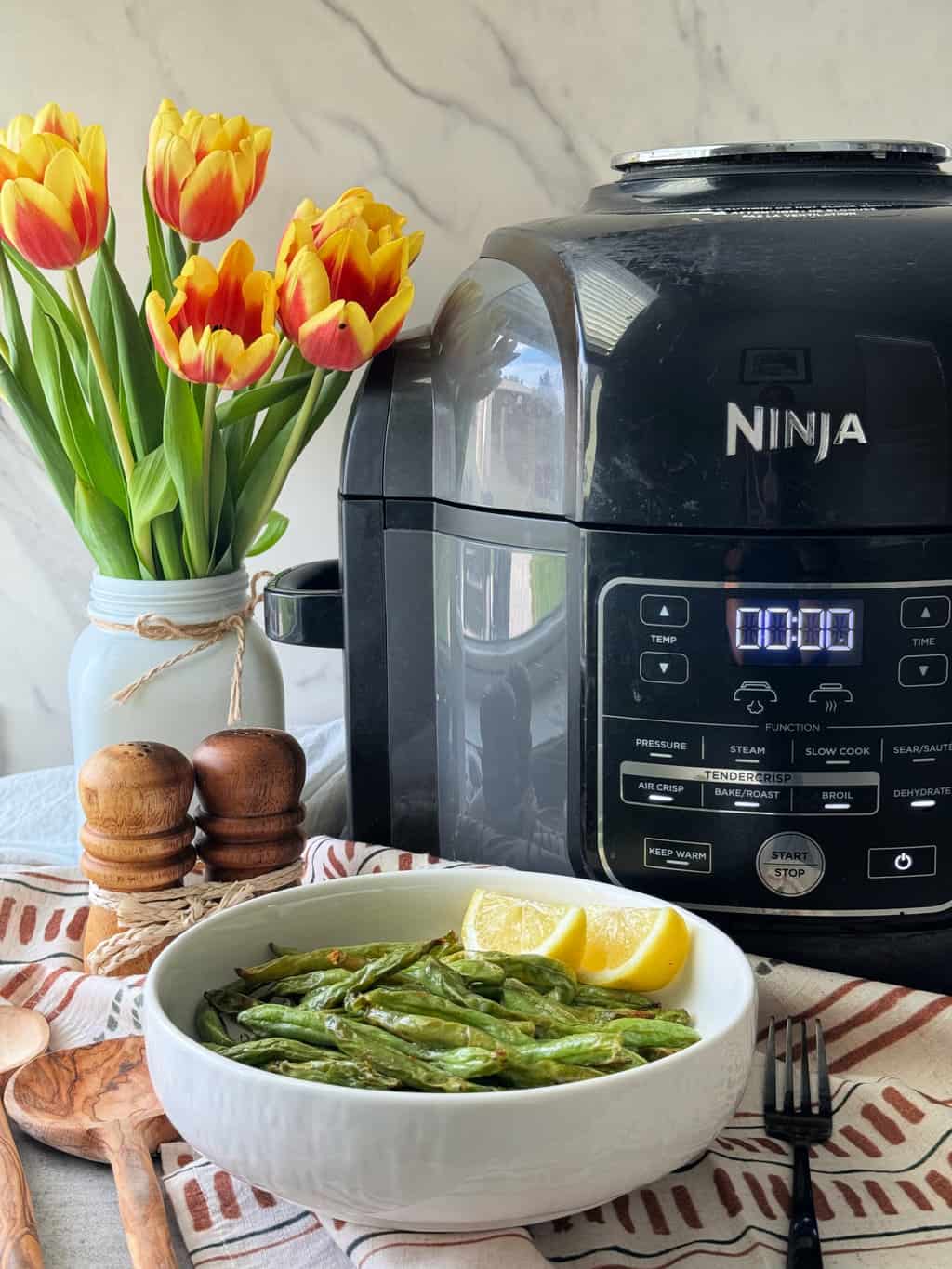 ninja-air-fryer-green-beans in bowl with lemon wedges