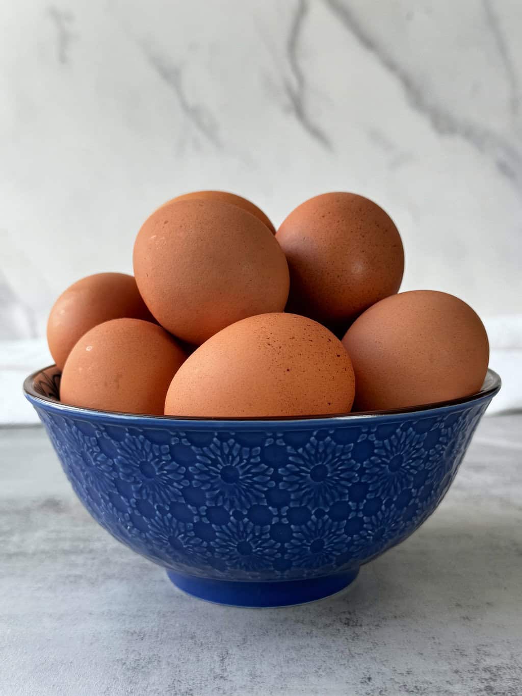 blue bowl full of brown eggs