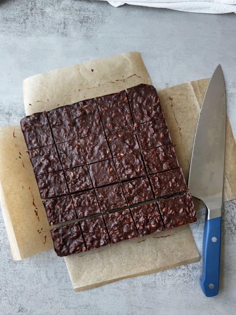 firm set chocolate oatmeal on parchment paper with sharp knife cut into square bars