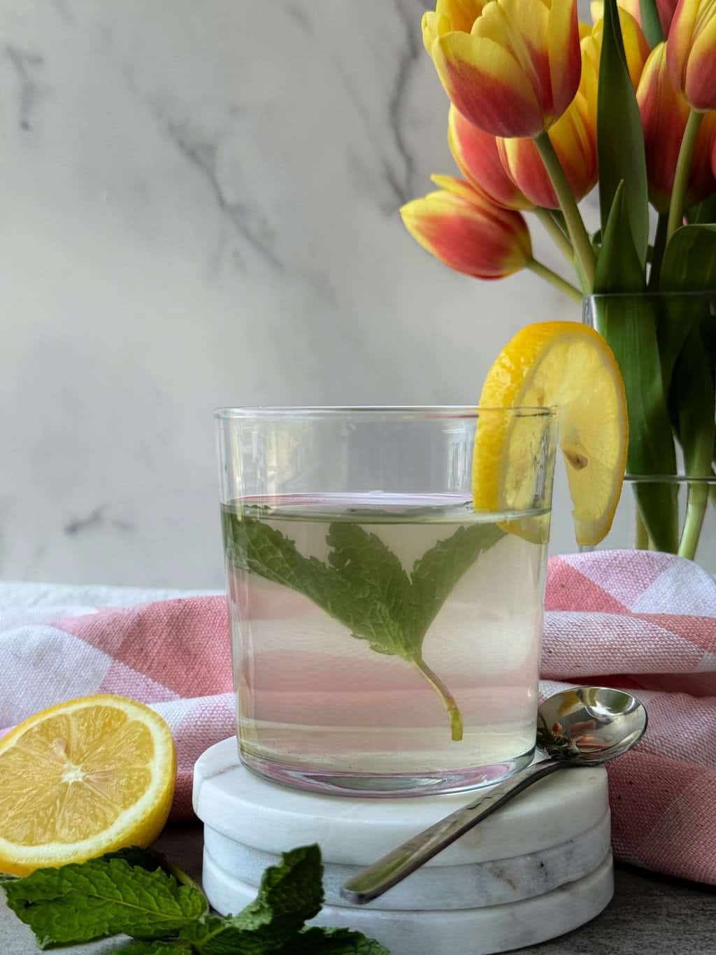 Apple Cider Vinegar Water Recipe with Lemon and Mint on white coaster and fresh lemon