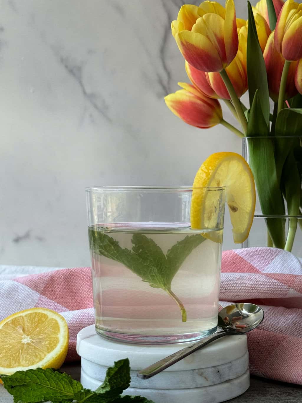 Apple Cider Vinegar Water Recipe with Lemon and Mint in a glass with flowers in background