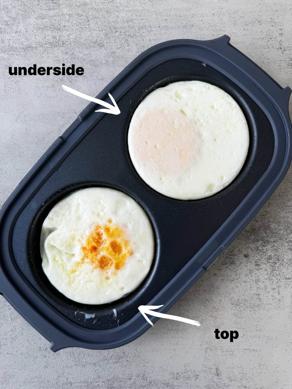 eggs in egg cooker, with one egg showing the top cooked and the other side showing the underside cooked
