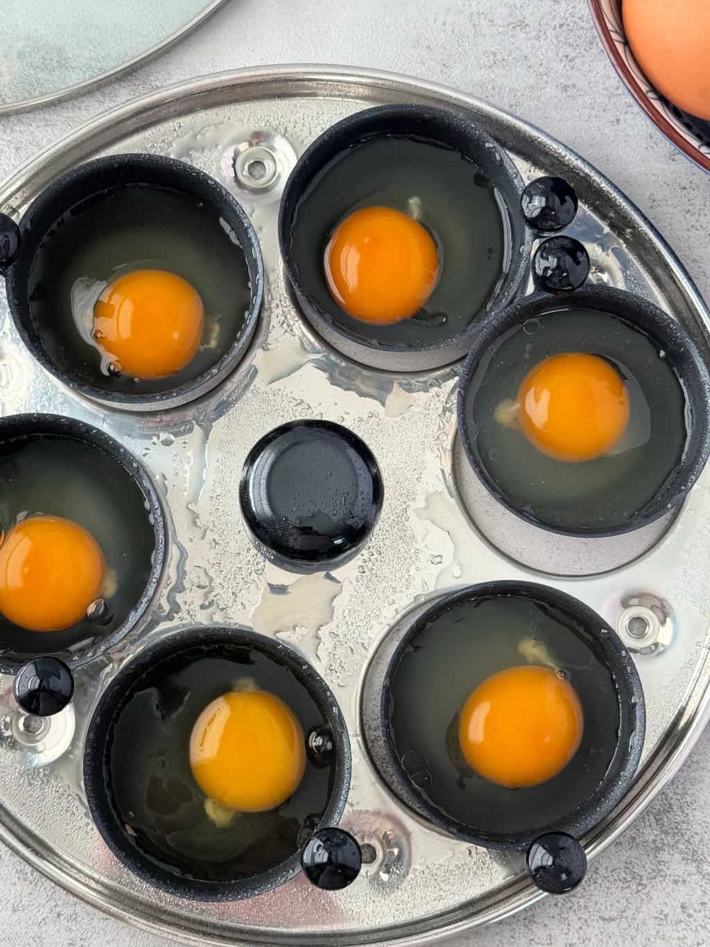 raw eggs in single poaching cups