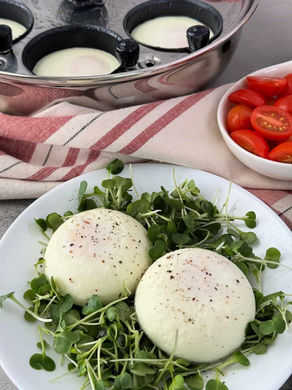 poached eggs cooked in an egg poacher pan in a plate with micro greens and tomatoes