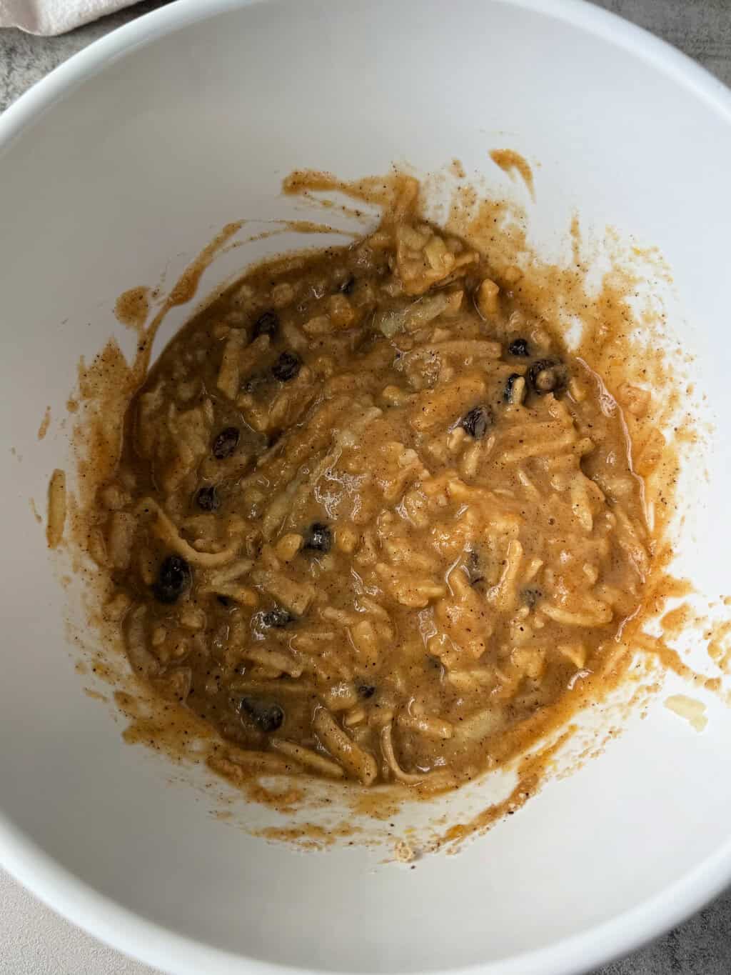 raw muffin batter with shredded apple and raisins mixed in