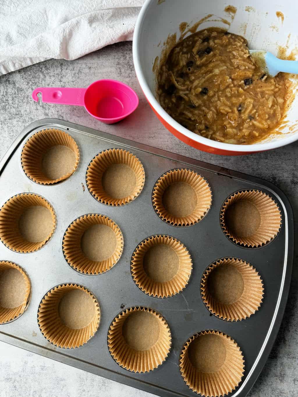 muffin batter in bowl with muffin pan lined with parchment paper liners
