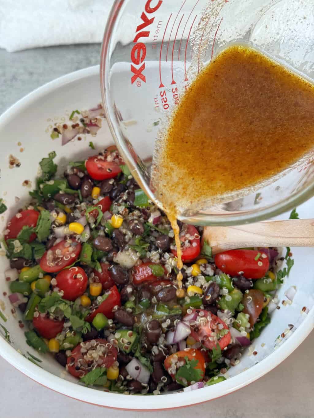 pour lime dressing into bowl with Black Bean and Quinoa Recipe