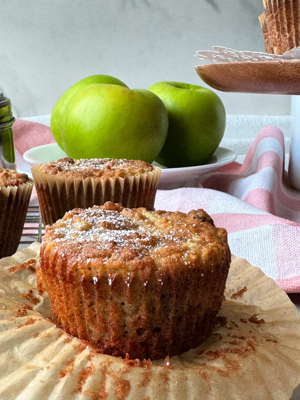 health apple muffin with paper lined peeled away and white powdered sugar on top