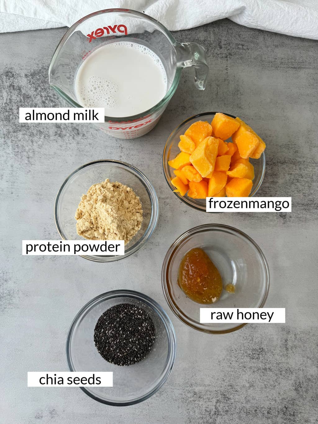 mango protein shake with vanilla protein powder ingredients in single glass dishes with labels. only 5 ingredients