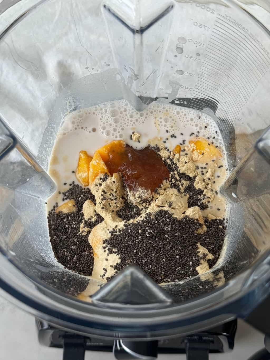 frozen mango protein smoothie ingredients in blender with protein powder